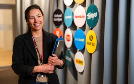 Kvinnlig medarbetare på Axfoods kontor framför logotyper för Axfoods olika bolag